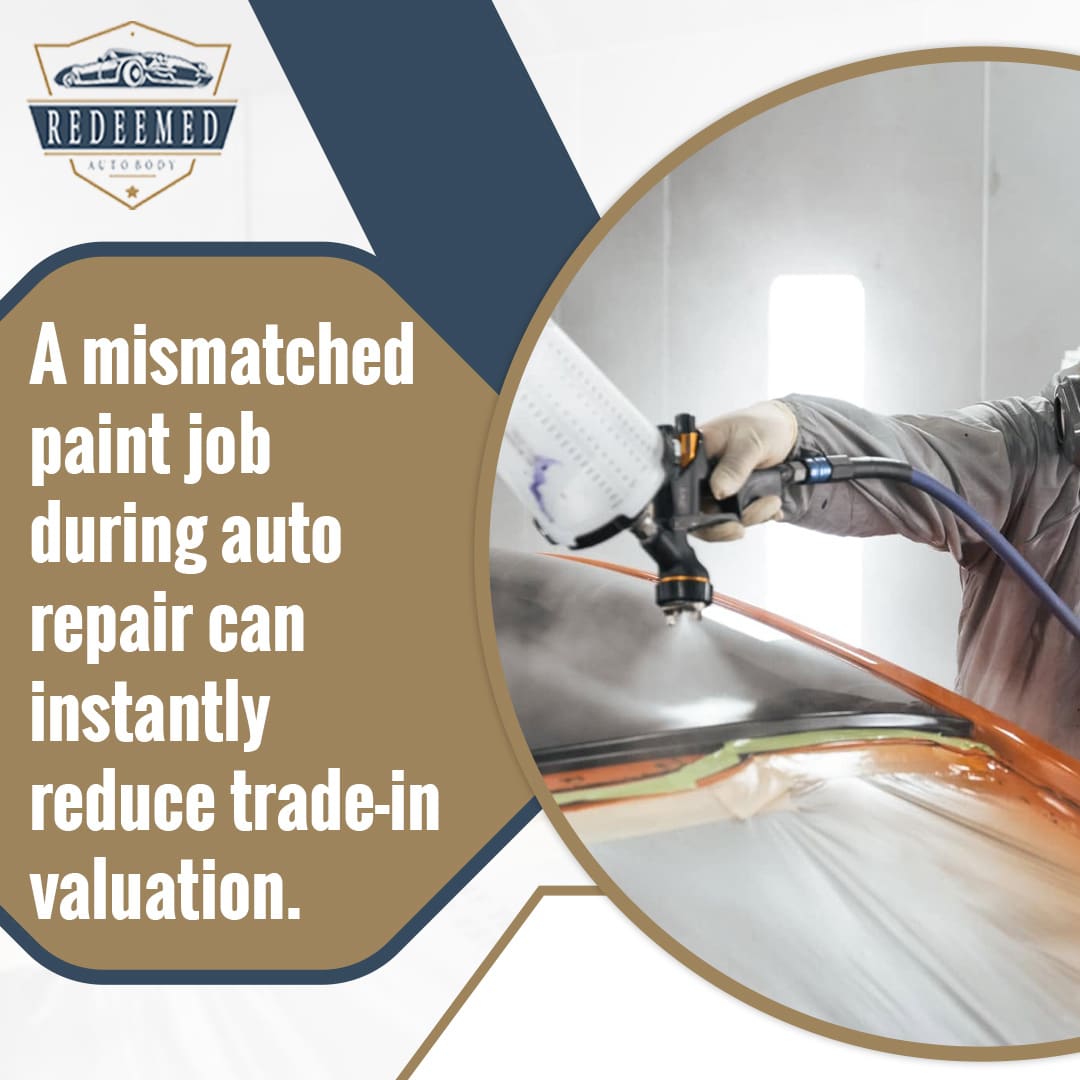 Professional auto body technician in protective gear spraying automotive paint onto a masked vehicle panel in a spray booth.
